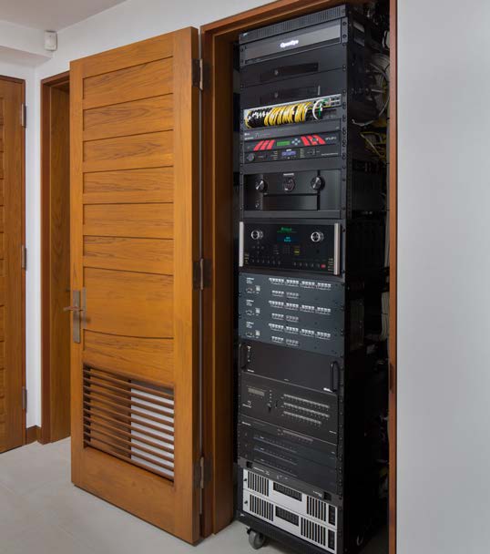 Back of the concealed equipment rack — meticulously bundled and labeled wiring feeds every hidden speaker and subwoofer in the room.